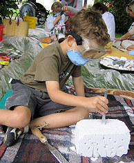 Foto: In einer Gruppe von Kindern betätigt sich ein kleiner Junge mit einem Gasbetonstein spielerisch als 'Bildhauer'.